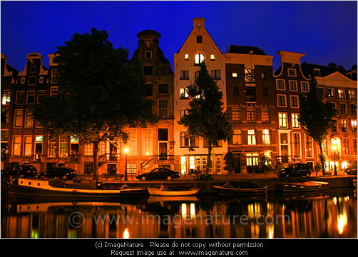 Typical Amsterdam houses at night with reflection in canal water