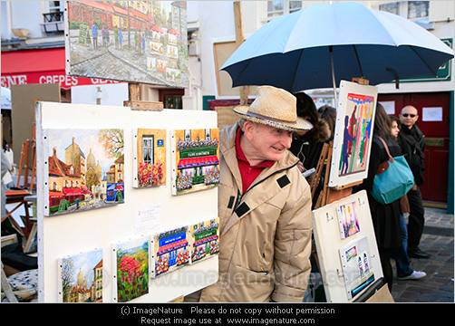 Photo of artist showing pictures at Montmartre in Paris